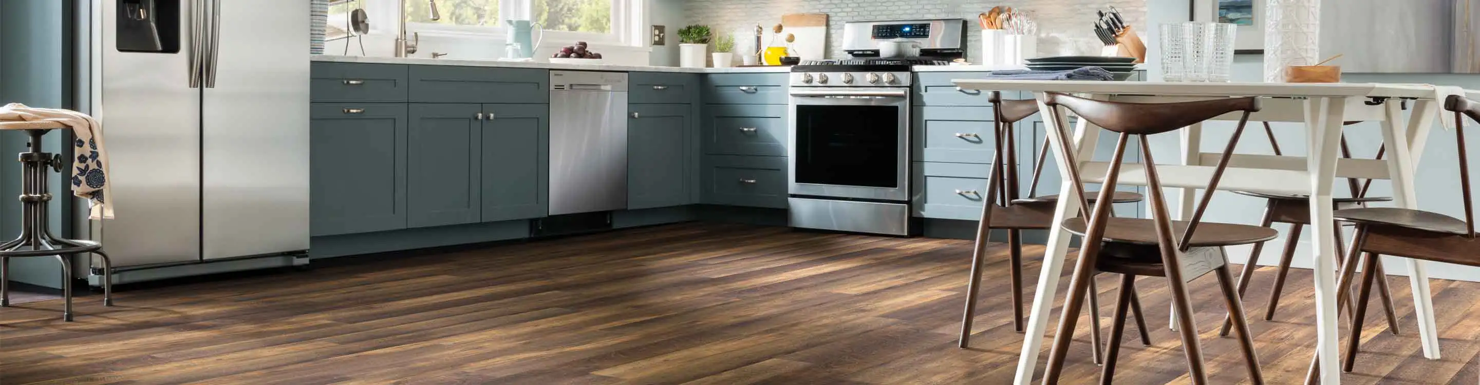 dark vinyl plank wood look flooring in kitchen with blue cabinets and dining table